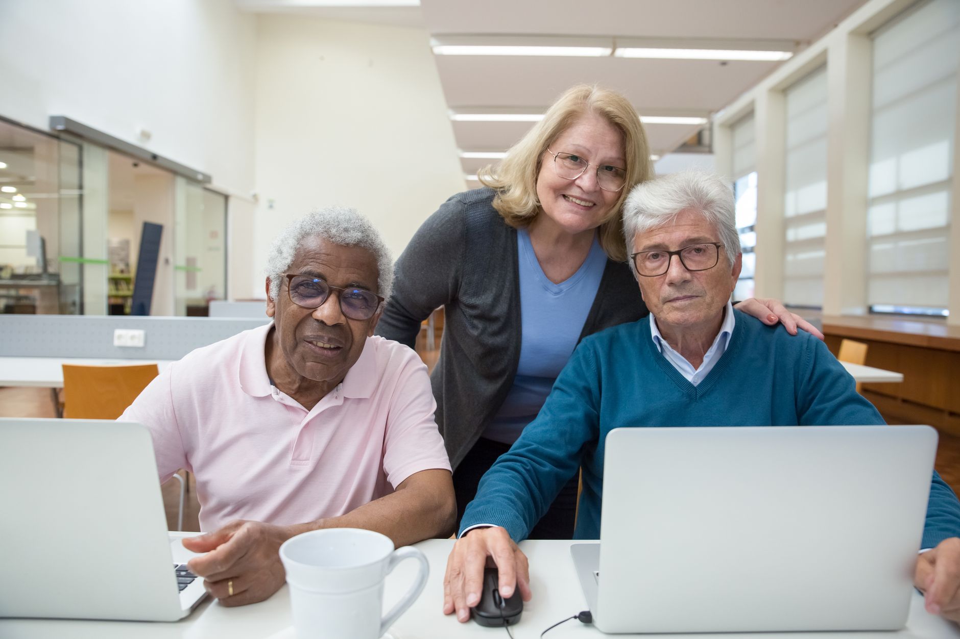 Tre allievi senior sorridono davanti ai laptop durante il corso